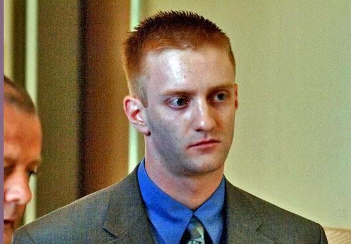 Christopher Porco appearing at court wearing a gray coat over a blue collared shirt and a tie with reddish hair.
