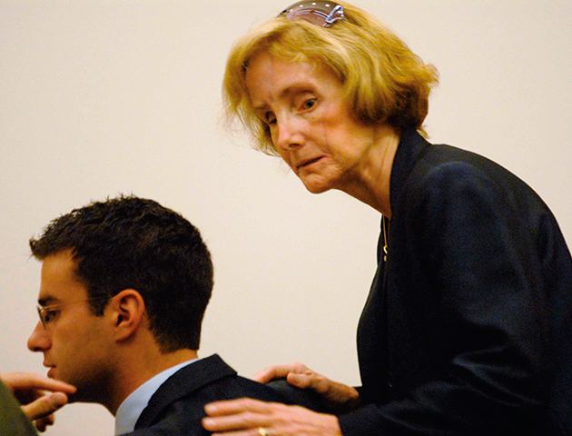 Joan Porco, Christopher Porcos mother, appearing in court with her hand over an attorney and wearing dark blue clothes and glasses in her head.