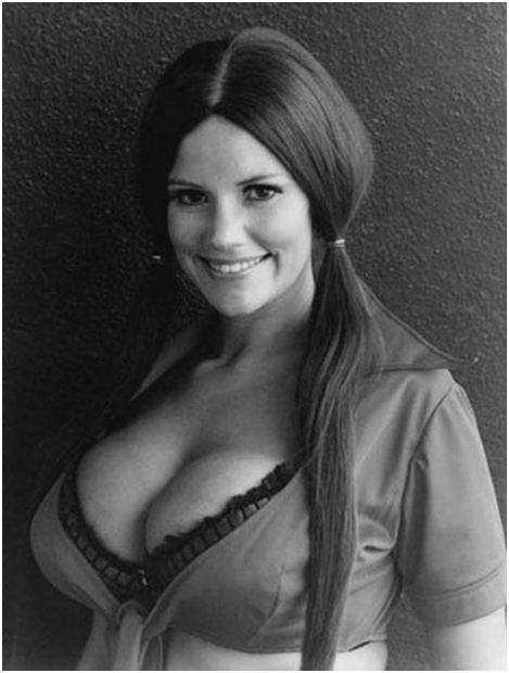 Christy Hartburg smiling, with long hair and wearing a sexy top showing her cleavage.