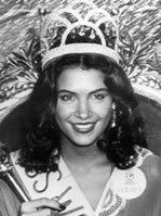 Cindy Breakspeare with a smiling face and curly hair, wearing a crown and a sash.