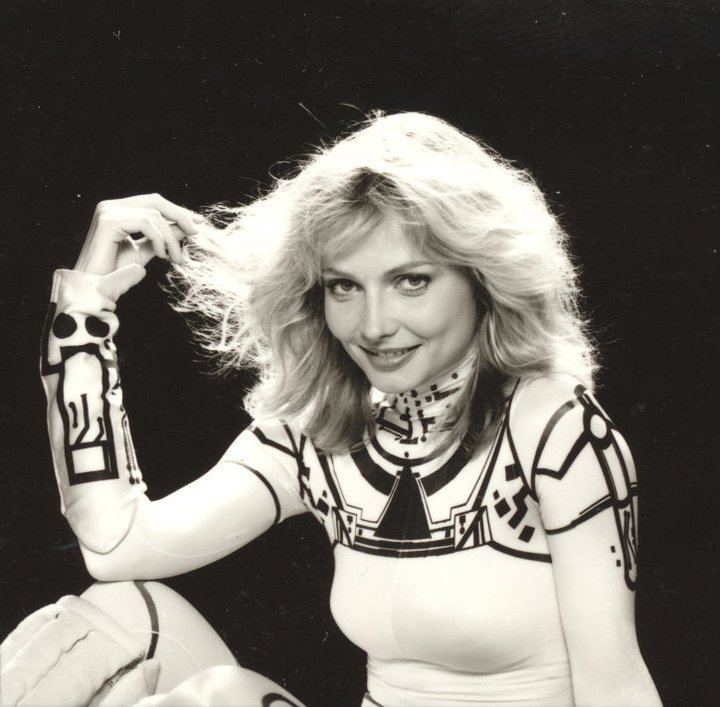 Cindy Morgan smiling while wearing a black and white long sleeve jumpsuit