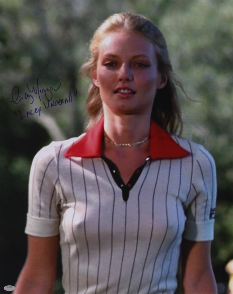 Cindy Morgan wearing a necklace and black and white polo shirt with a red collar and an autograph on the upper left