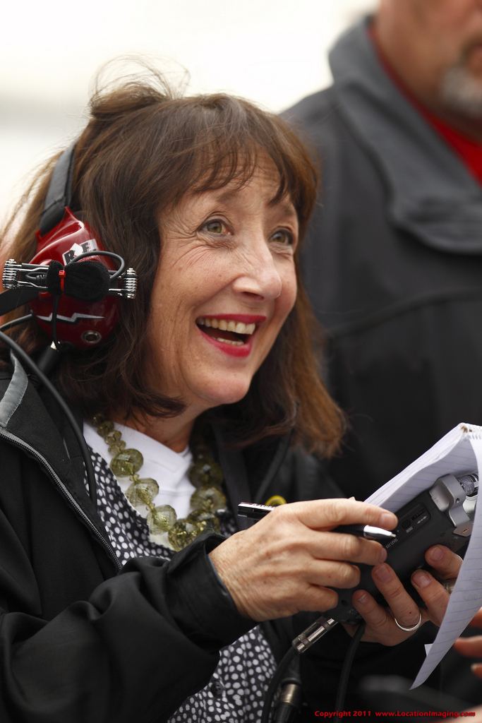 Claire B. Lang smiling during an event and wearing red headphones while holding a pen and notebook.