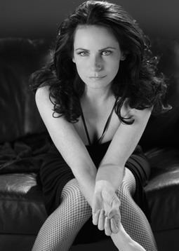 Clare Calbraith sitting on a couch while wearing mini dress and net stockings