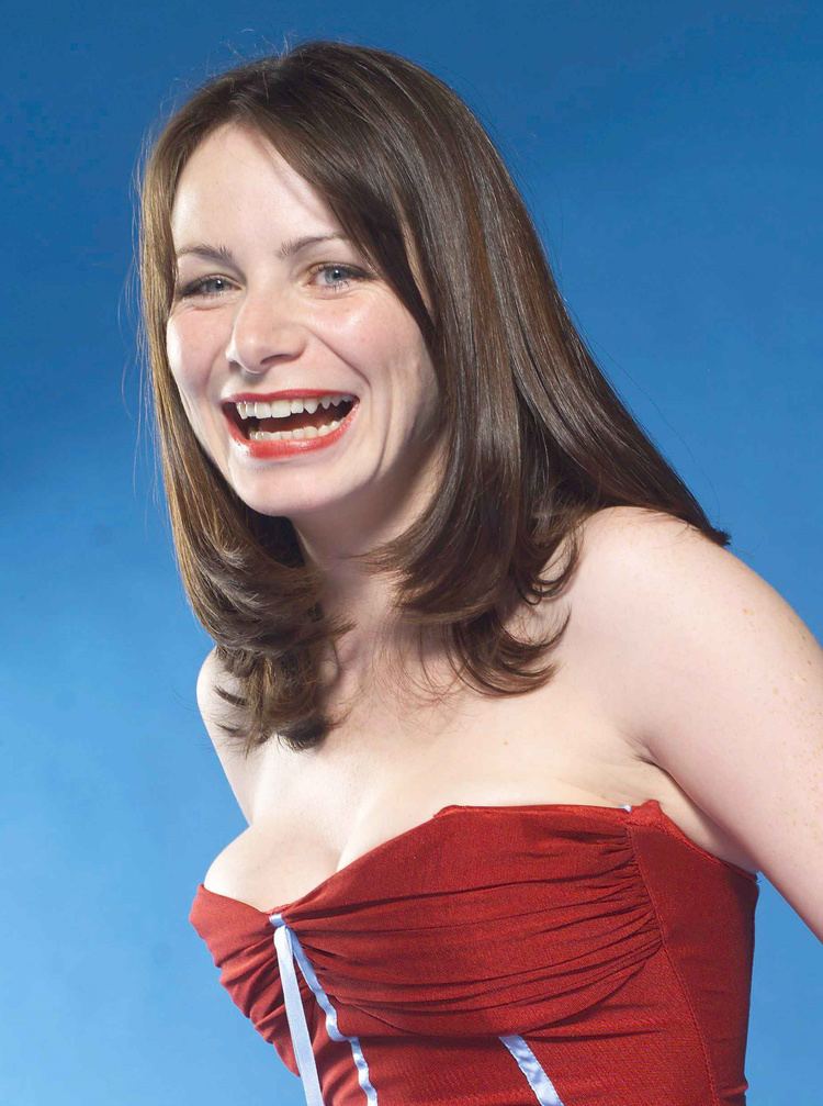 Clare Calbraith laughing while wearing red dress