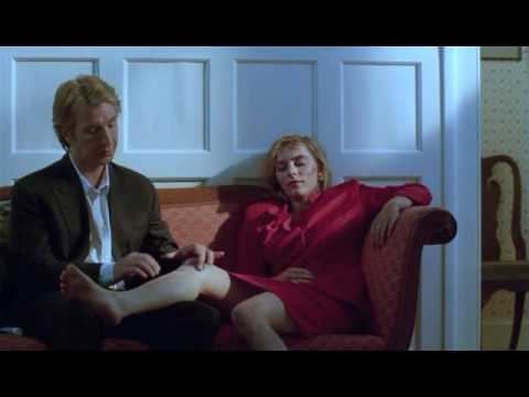 Saskia Reeves sitting on the couch with Alan Rickman and she is wearing red long sleeve dress in a scene from the 1991 film, Close My Eyes