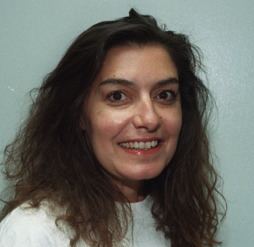 Connie Hamzy smiling and wearing a white shirt with her thick hair.