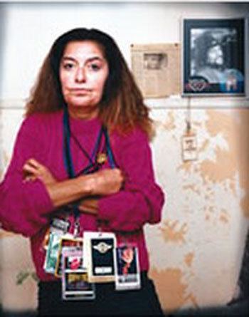 Connie Hamzy posing with her arms crossed and wearing a purple long-sleeved shirt and wearing multiple ID's.