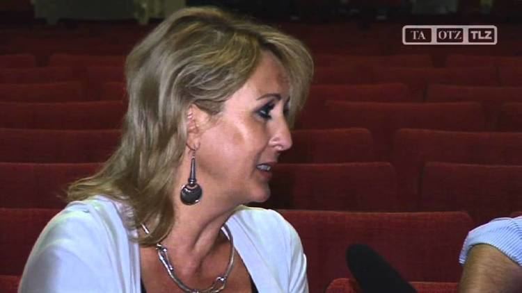 Corinne Hofmann with blonde hair and wearing a white shirt during an interview.