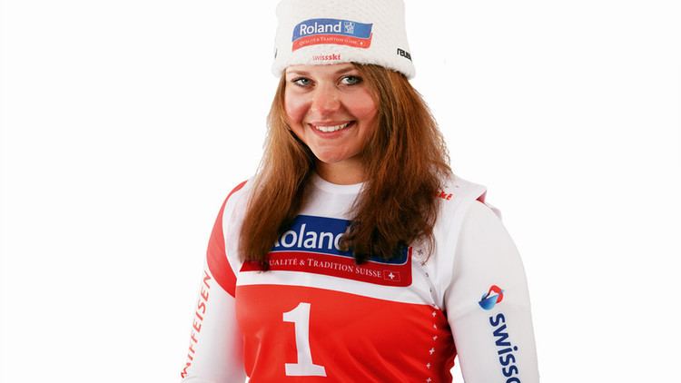 Corinne Suter smiling with her brown hair wearing a white bonnet with Roland print on it and white with red long sleeve with Roland print with #1 logo on it