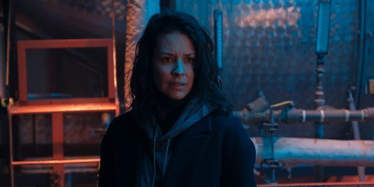 Evangeline Lilly with a serious face while wearing black coat and gray hoodie in a scene from the 2021 crime thriller film, Crisis