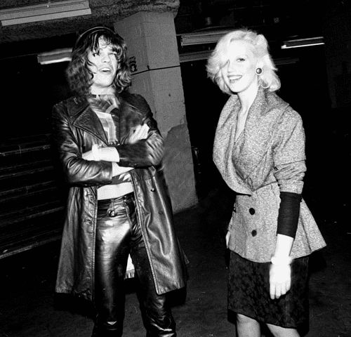 Cyrinda Foxe smiling and wearing blouse and skirt while David Johansen wearing black leather coat