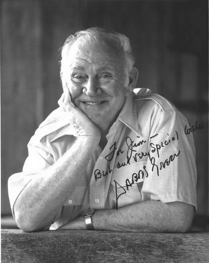 Portrait of Dabbs Greer with an autograph in which he is smiling and hand on his chin while wearing a polo and wristwatch