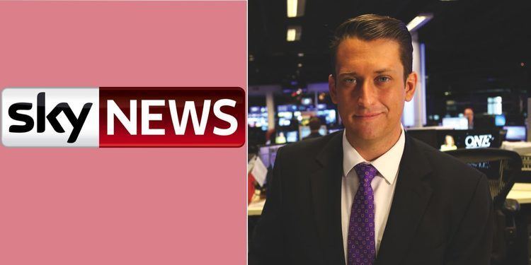 On left is the logo of sky news, which has a black and white font with a white and red background. On right is Dan Bourchier smiling, has black hair, at the back are tv monitors, he is wearing a white long sleeve, and a violet necktie with a design under a black suit.
