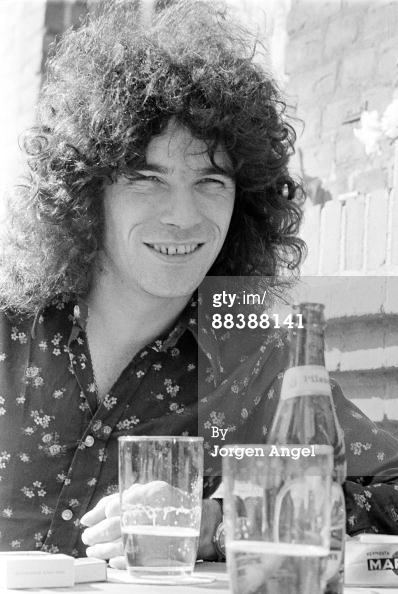 Dan McCafferty smiling with long curly hair and wearing floral long sleeves