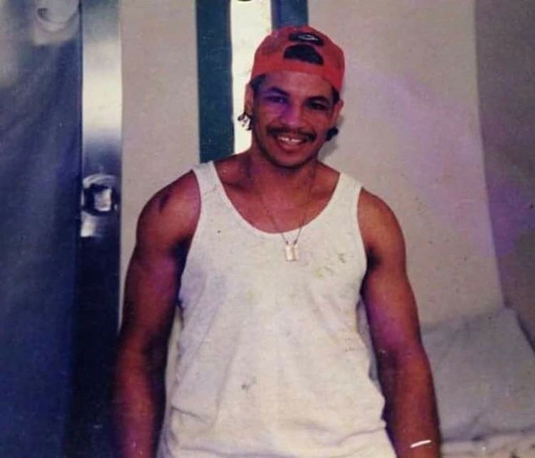 Dandeny Muñoz Mosquera smiling and wearing red cap and white sando