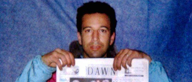Daniel Pearl holding a newspaper while wearing a blue jacket