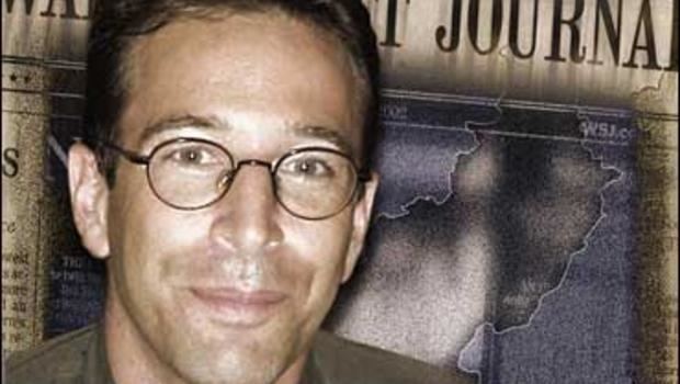 Daniel Pearl smiling while wearing eyeglasses and brown long sleeves