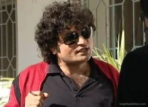 Danish Nawaz with curly hair and wearing black shades, red jacket and black polo shirt