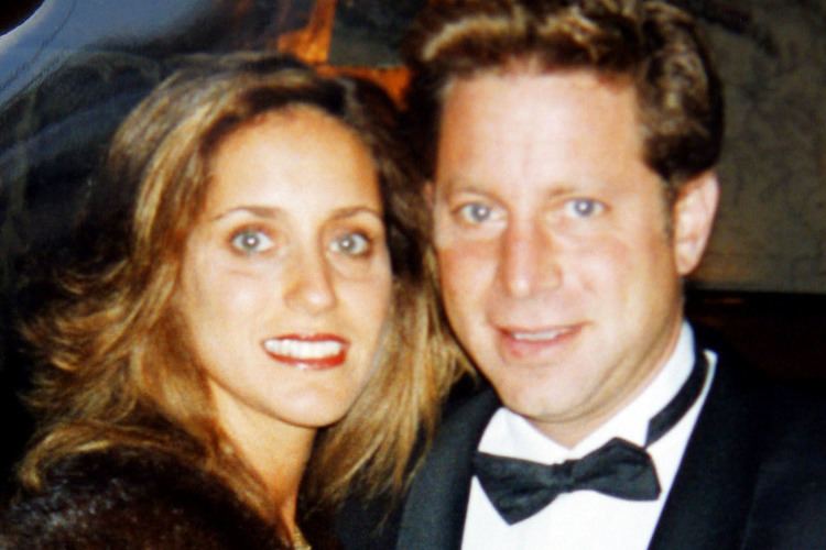 Danny Porush wearing a black suit and a bow and tie with a woman with wavy blonde hair.