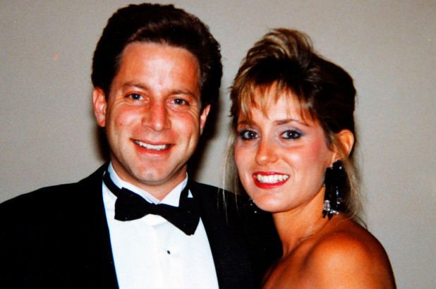 Danny Porush wearing a black suit and a bow and tie with a woman wearing earrings.