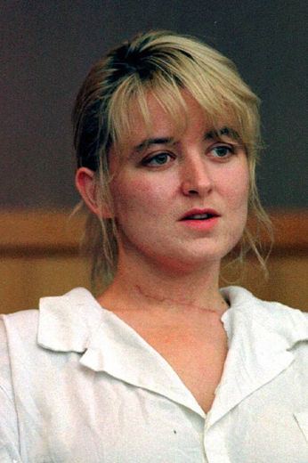 Darlie Routier looking serious and wearing a white shirt showing  a mark of the cut on her throat