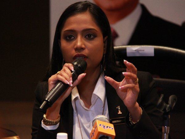 Dato Geethanjali G wearing a white shirt and black suit while holding a microphone