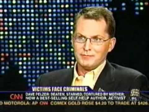 Dave Pelzer, in a news report with a head title "Victims face Criminals", looking seriously while wearing eyeglasses and yellow long sleeve under a black coat