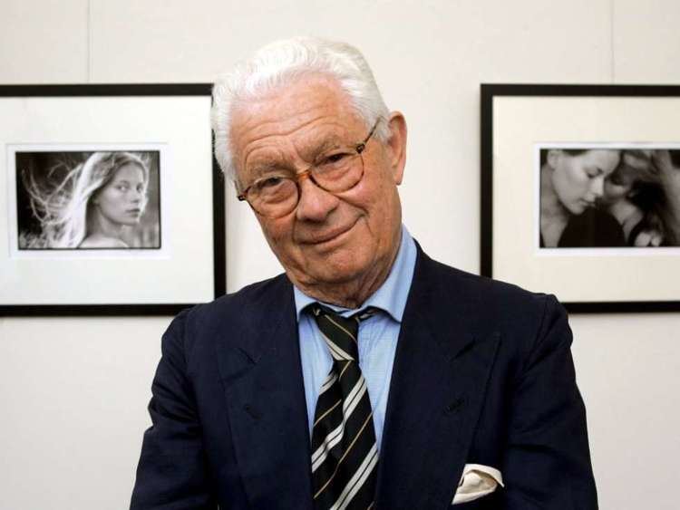 David Hamilton (photographer) wearing a blue long-sleeved shirt, a suit, a pair of eyeglasses, and a tie