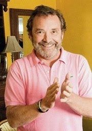 David Henesy smiling with a beard and wearing a pink shirt and a watch in his wrist.