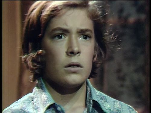 David Henesy with long hair looking at something and wearing a jean jacket in a scene from House of Dark Shadows, 1970.