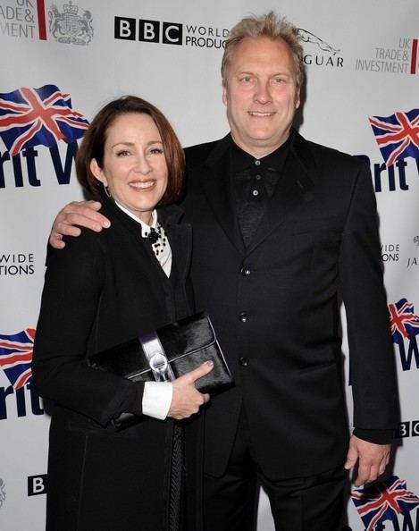 David Hunt wearing a black suit together with Patricia Heaton wearing a black and white dress while carrying a black bag.
