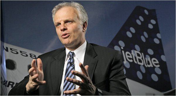 David Neeleman wearing a black suit with a blue striped tie during an interview.