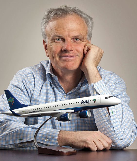David Neeleman wearing light blue long sleeves with a toy plane in front of him.