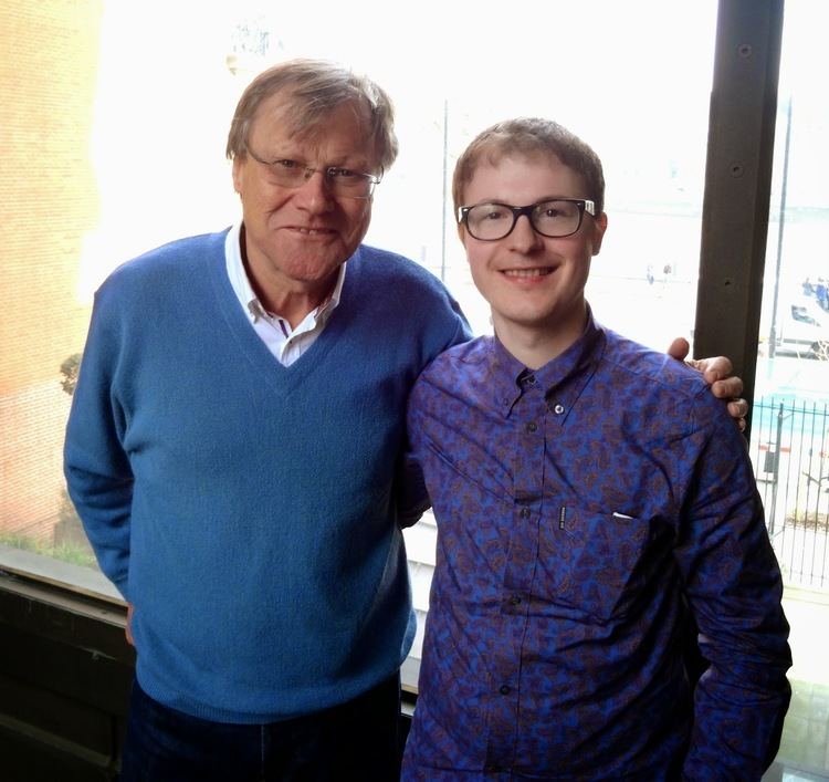 David Neilson and Martin Leay are smiling while David is wearing a blue sweater and eyeglasses and Martin is wearing black and blue long sleeves