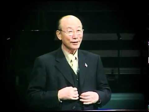 David Yonggi Cho fixing himself to give a talk on stage and wearing black suit.