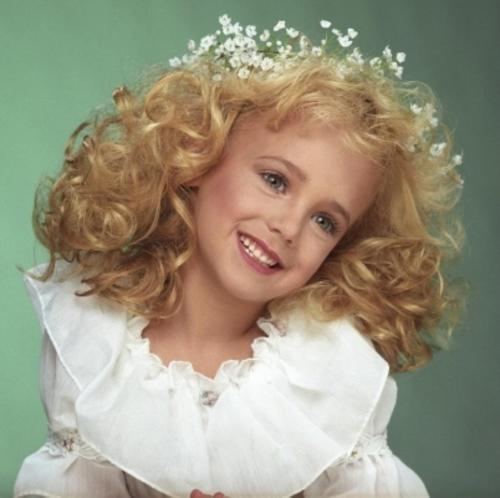 JonBenét Ramsey with curly blonde hair and wearing a white dress.