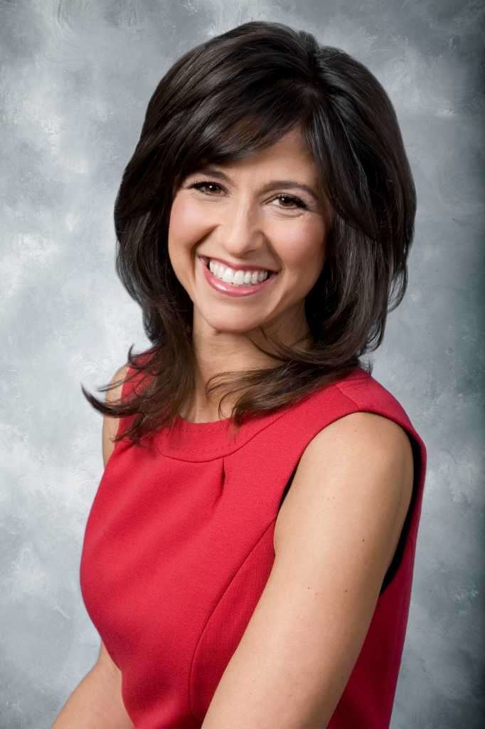 Deb Placey with a big smile while wearing a red dress