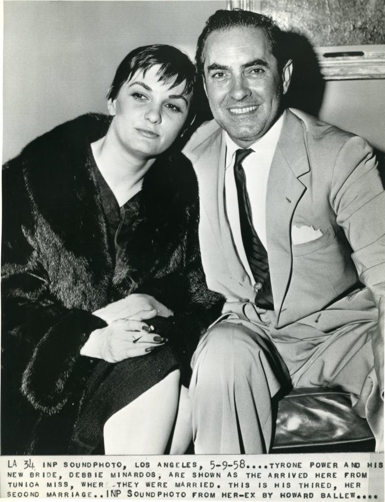 Deborah Minardos wearing a black long-sleeved shirt with her husband Tyrone Power wearing a white shirt, a suit, and a tie