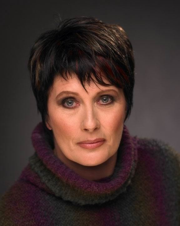 Debra Byrne in her short hair while wearing gray and violet turtle neck blouse
