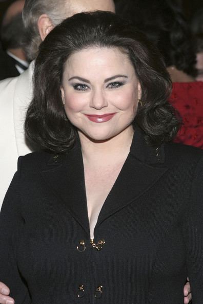 Delta Burke smiling while wearing a black long sleeve dress