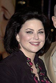 Delta Burke smiling while wearing a black dress with roses design on the neckline