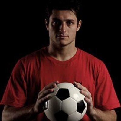 Denis César holding a ball while wearing red shirt