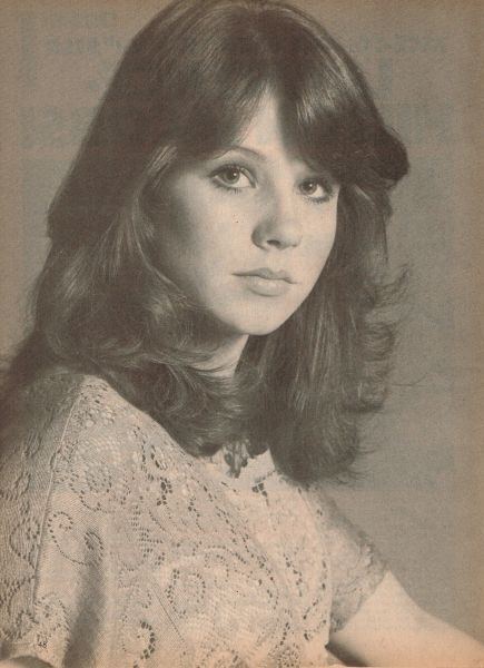 Young Denise Miller with wavy hair and wearing a blouse