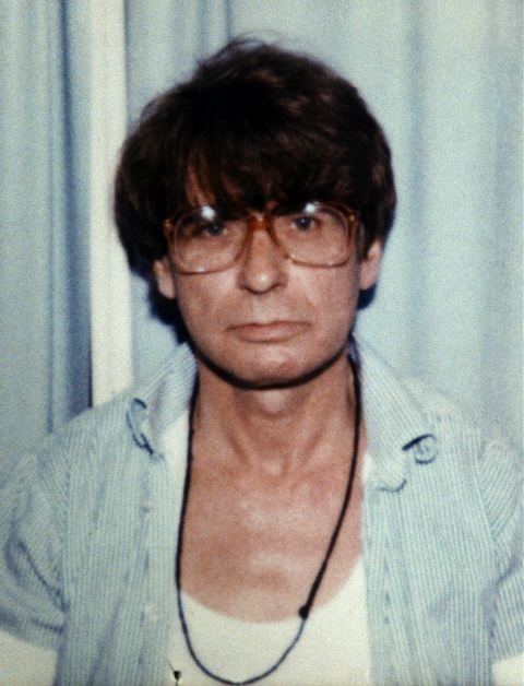 Dennis Nilsen wearing blue striped long sleeves, white sando, a black necklace, and eyeglasses