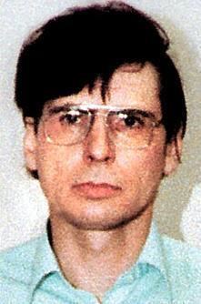 Mug shot of Dennis Nilsen while wearing eyeglasses and light blue long sleeves
