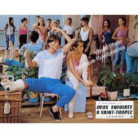 Philippe Caroit wearing striped t-shirt and blue pants with Stephanie Billat in her pink top and white leggings while sitting on a chair, scene from Deux enfoirés à Saint-Tropez