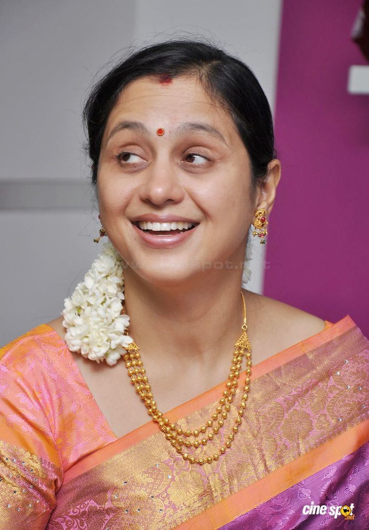 Devayani Jayadev wearing earrings, a necklace, and a color orange and purple dress.