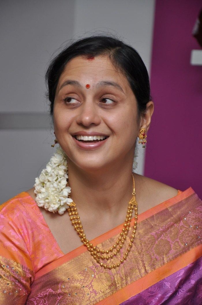 Devayani Jayadev wearing earrings, a necklace, and a color orange and purple dress.