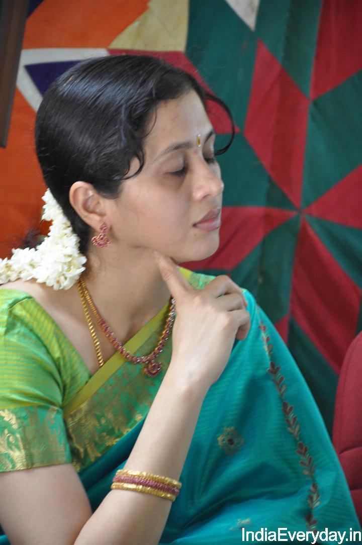 Devayani Jayadev with a flower on her hair, wearing earrings, a necklace, bracelets, and a color green and blue dress.